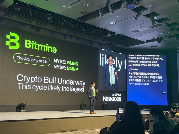 A conference presentation by Bitmine at KBW2026, showing slides about 'The Alchemy of 5%' with NYSE tickers BMNR and BMNP, displaying 'Crypto Bull Underway - This cycle likely the largest' with the speaker on stage.