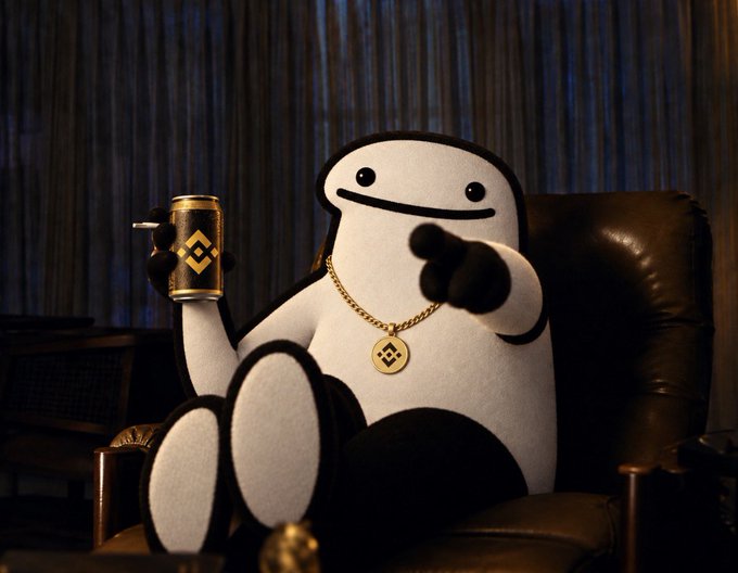 A plush mascot with the Binance logo on its cup and medallion lounges in a leather chair while pointing at the viewer, visually personifying the meme's claim that crypto giants are quietly endorsing the $FLORK token. The image reinforces the post's conspiratorial tone by giving the "three giants" (Binance, CoinMarketCap, Litecoin) a cheeky, knowing mascot figure.
