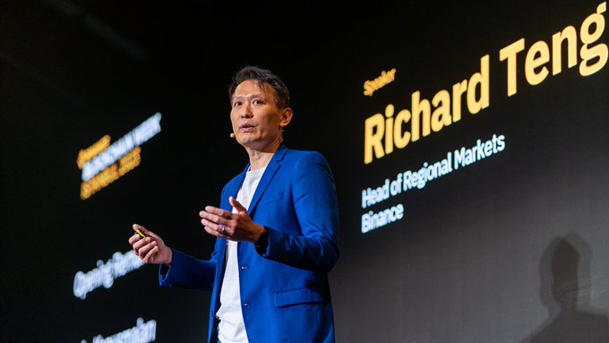A man in a blue blazer giving a presentation on stage, with a screen behind him identifying him as 'Speaker Richard Teng, Head of Regional Markets, Binance'.
