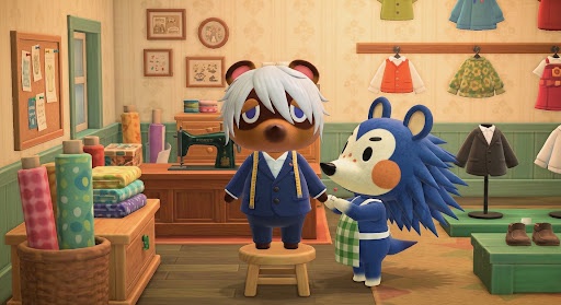 An Animal Crossing scene showing a white-haired panda-like character standing on a stool while a blue hedgehog character appears to be tailoring their clothes in a shop.