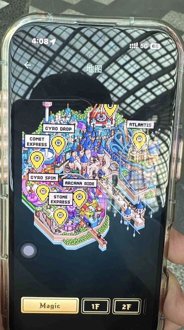 A smartphone displays a colorful theme park map with location pins labeled 'GYRO DROP', 'COMET EXPRESS', 'GYRO SPIN', 'STONE EXPRESS', 'ARCANA RIDE', and 'ATLANTIS', with floor selection options 'Magic', '1F', and '2F' at the bottom.