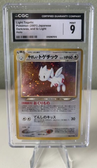 A CGC-graded Japanese Light Togetic Pokémon card from the 2001 'Darkness, and to Light' Holo set, graded Mint 9, displayed in a protective case.