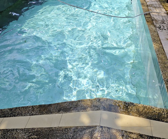 The image shows a swimming pool with clear blue water, surrounded by tiles that create a border around its edge. The pool appears to be empty or nearly empty, as there are no people visible in the scene. The photo has been captioned "Good morning CT builders! ImpactShare is almost over. How's everyone doing? What'S your current rank?" and "Super bullseye on @XOOBNetwork". This suggests that someone took a picture of this pool, possibly to share with others or for personal use. The image's content seems unrelated to the post about builders in CT, but it could be an interesting visual representation of a swimming pool area.