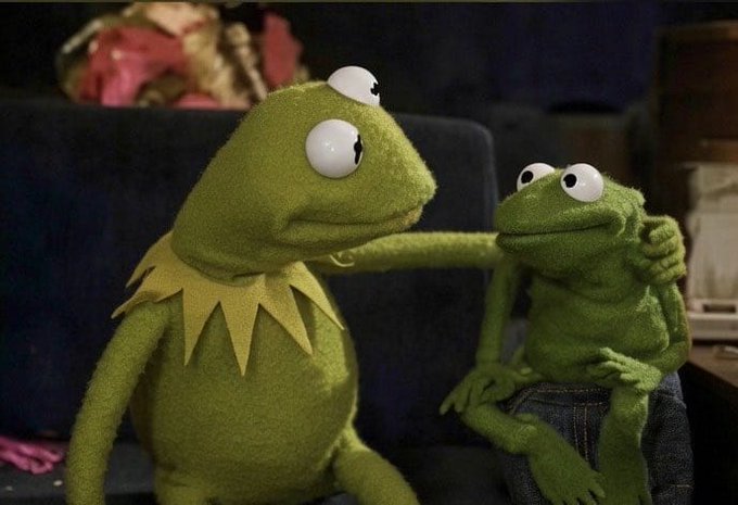 Two Kermit the Frog puppets, one larger and one smaller, sit together with their arms around each other.