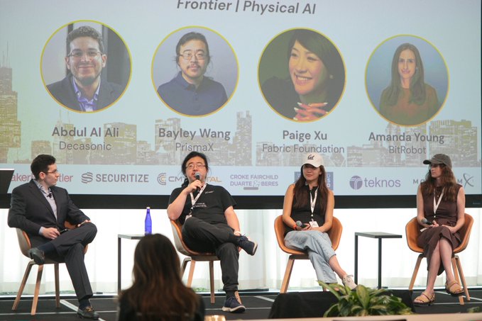 A panel discussion titled 'Frontier | Physical AI' featuring four speakers on stage, with their photos and names (Abdul Al Ali from Decasonic, Bayley Wang from PrismaX, Paige Xu from Fabric Foundation, and Amanda Young from BitRobot) displayed on a screen behind them.