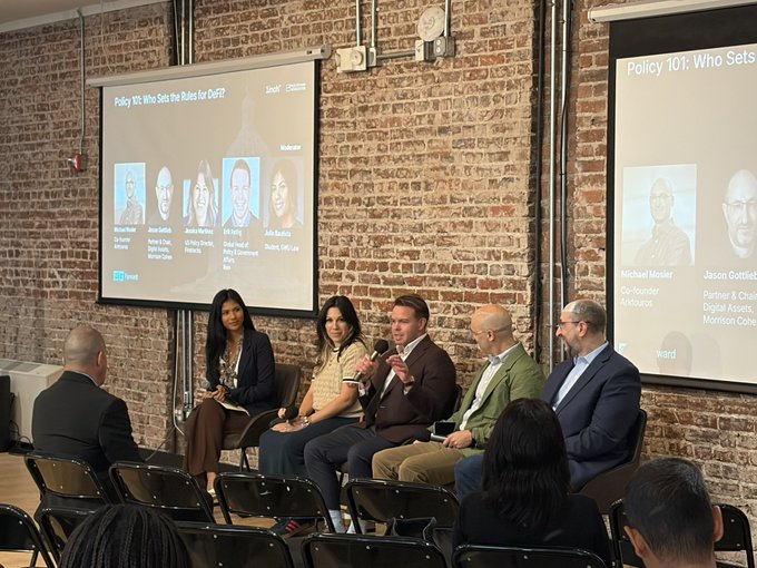 A panel discussion titled 'Policy 101: Who Sets the Rules for Gutf?' featuring speakers Michael Mosier, Jason Gottlieb, and others seated before an audience in a brick-walled room.