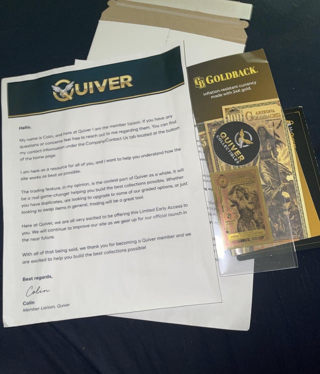 A handwritten welcome letter from "Colin, Member Liaison, Quiver" sits on a dark surface alongside a promotional packet for "Goldback" currency (described as "Inflation resistant currency made with 24K gold"), visually confirming the post's claim that Quiver is giving away free Goldbacks to new members.