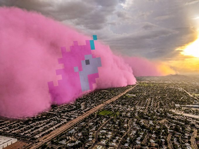 A surreal aerial view of a cityscape with massive plumes of pink smoke containing pixelated blue and gray cat-like shapes billowing across the landscape at sunset.