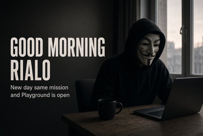 A figure wearing a Guy Fawkes mask and black hoodie sits at a desk with a laptop and coffee mug, next to the text 'GOOD MORNING RIALO' and 'New day same mission and Playground is open'.