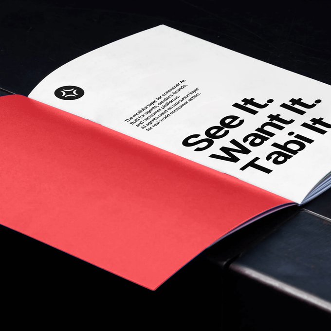 An open book or brochure with a red page on the left and a white page on the right displaying the text "See It. Want It. Tabi It." along with smaller product description text and a logo. The branded slogan "Tabi It" connects to the post's playful question about "meeting Tabi," suggesting Tabi is the name of a product or brand featured in the booklet.