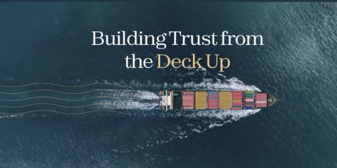 An aerial view of a container cargo ship sailing through blue ocean water, with the overlay text 'Building Trust from the Deck Up.'