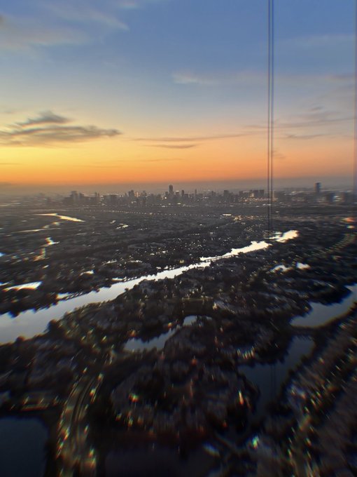 The image shows an aerial view of a cityscape with a river running through it, surrounded by buildings. The sky overhead features a stunning sunset or sunrise, with a line of power poles standing tall in the background against the beautiful backdrop. There is also some water visible in the bottom right corner of the photo. In the accompanying post about the StakeMarket, there are several posts related to the stock market, including one that has the number "270" on it. The main image features multiple words or phrases such as "Post", "City", and "Post".