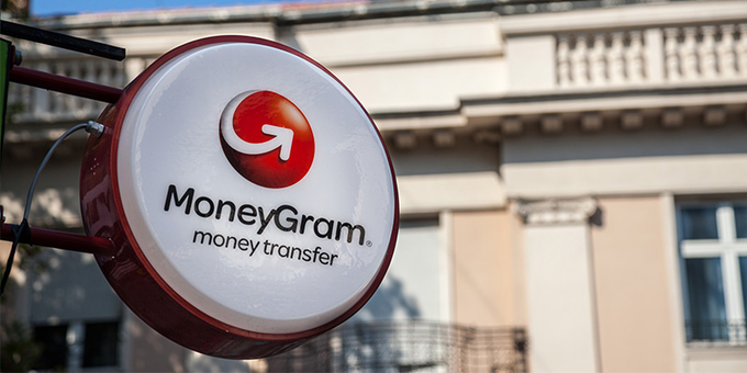 A circular MoneyGram money transfer sign mounted on the exterior of a building.