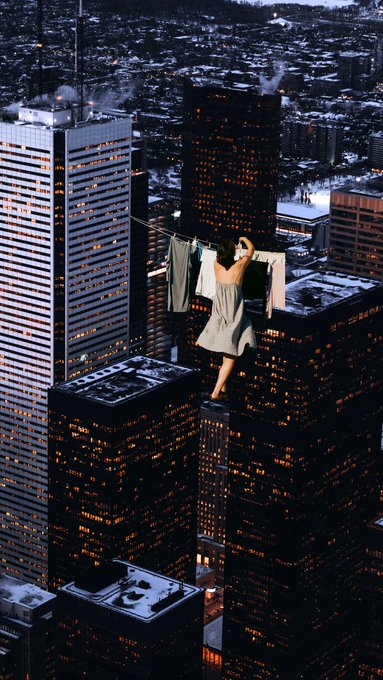 A surreal, gravity-defying image shows a woman in a gray dress hanging laundry on a clothesline strung between towering skyscrapers above a nighttime cityscape, evoking the dreamy, domestic-routine concept of the "Dream Routine" NFT collection.