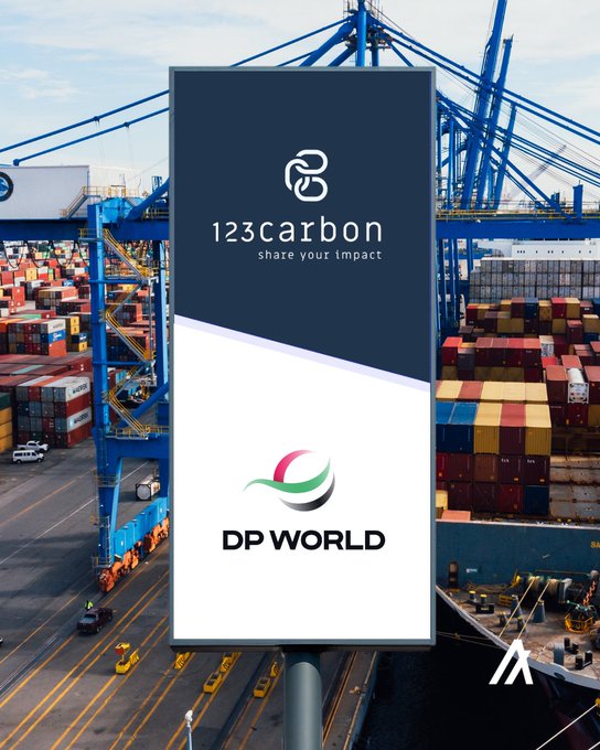 A billboard advertisement at a shipping port displays logos for '123carbon (share your impact)' and 'DP WORLD' against a backdrop of shipping containers and cranes.