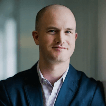 A clean-cut, bald man in a navy blazer and patterned shirt smiles slightly at the camera in a professional portrait, matching the image of Coinbase CEO Brian Armstrong referenced in the accompanying post about his criticism of the WSJ regarding the Clarity Act.