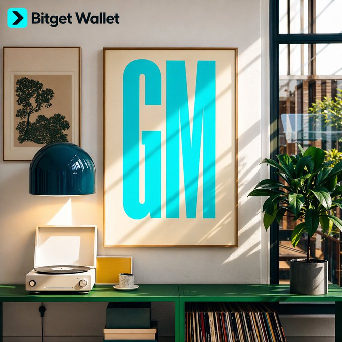 An advertisement for "Bitget Wallet" showing the letters "GM" in teal inside a framed poster, displayed above a green console with a record player, blue lamp, and a potted plant.