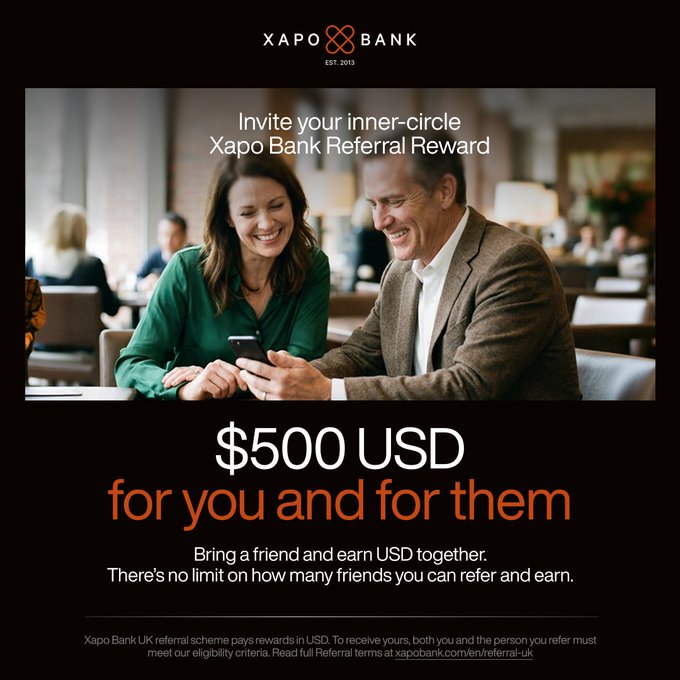 A Xapo Bank advertisement promoting a referral reward of $500 USD for both the referrer and the referred friend, featuring a couple looking at a smartphone in a restaurant setting.