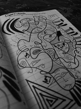A black and white photograph of an open notebook with abstract doodles and the text 'Cool Huh' written on the page.