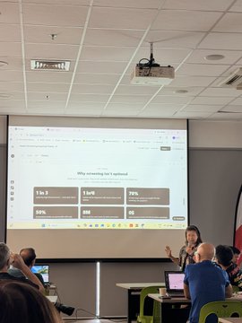 A presenter stands in a conference room next to a projected slide titled 'Why streaming isn't optimized' that shows statistics including '5 to 7 times slower', '1 to 4% [engagement]', and '70% [completion rate]'.