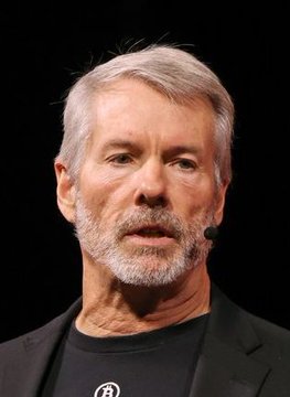 Michael Saylor, the executive chairman of Strategy (formerly MicroStrategy), is shown wearing a black t-shirt featuring the Bitcoin logo, reflecting his well-known advocacy for the cryptocurrency as the company continues its aggressive Bitcoin accumulation strategy.