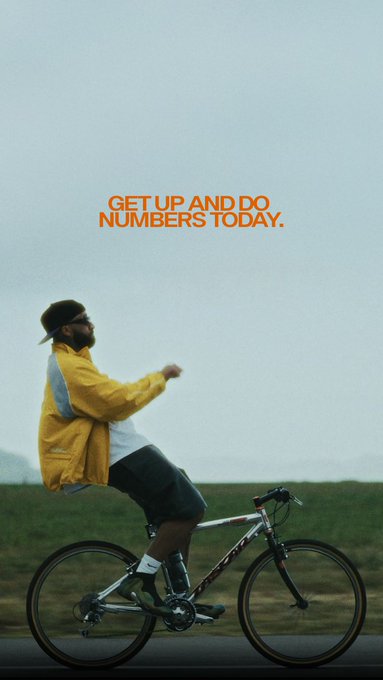 A motivational poster featuring a man in a yellow jacket riding a bicycle through a misty landscape with the text 'GET UP AND DO NUMBERS TODAY.' in orange.