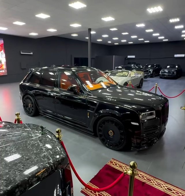 The image features a luxurious black luxury car parked inside a large showroom with multiple cars around it. The car has a shiny exterior and is surrounded by other high-end vehicles, creating an atmosphere of sophistication and elegance. The caption reads "Wallchain Select", which suggests that this could be a part of the "Wallchain" brand or a new collection from the brand's expansion into luxury cars. This implies that the focus on what is in the image is on the luxurious car and its surroundings, highlighting the brand's commitment to providing high-quality, stylish vehicles for their customers.
