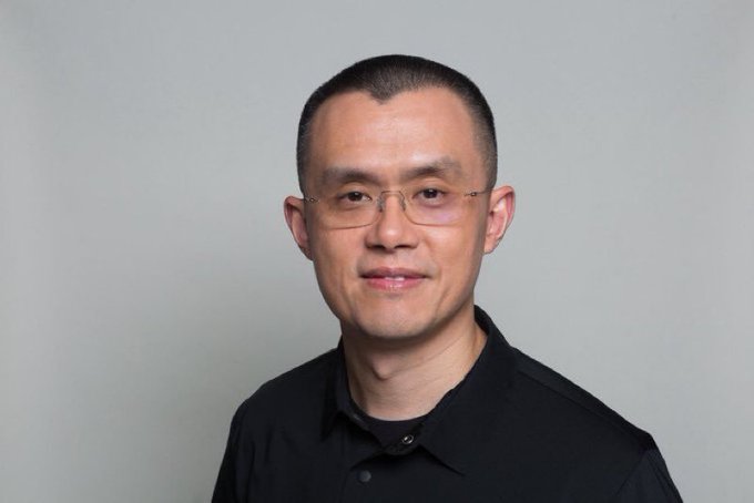 A man with short hair and rimless glasses smiles subtly while wearing a black polo shirt against a plain gray background. The accompanying caption appears to attribute the quote about crypto enabling early retirement to Binance founder Changpeng Zhao, commonly known as CZ.
