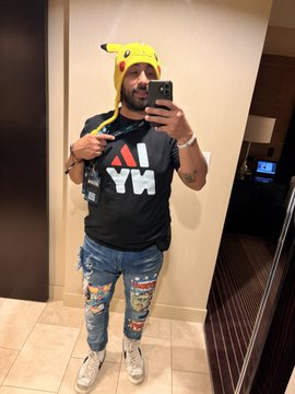 Mirror selfie of a man wearing a Pikachu hat, gray "AYW" t-shirt, ripped jeans, and white sneakers.