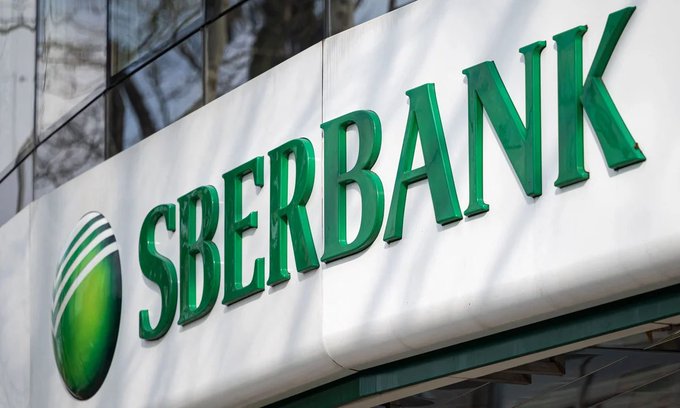 An exterior sign displays the green 'SBERBANK' logo and name mounted on a white building facade.
