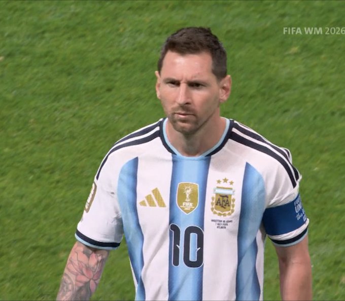 Lionel Messi wearing the Argentina national team jersey with number 10 on a soccer field, with 'FIFA WM 2026' text visible in the corner.