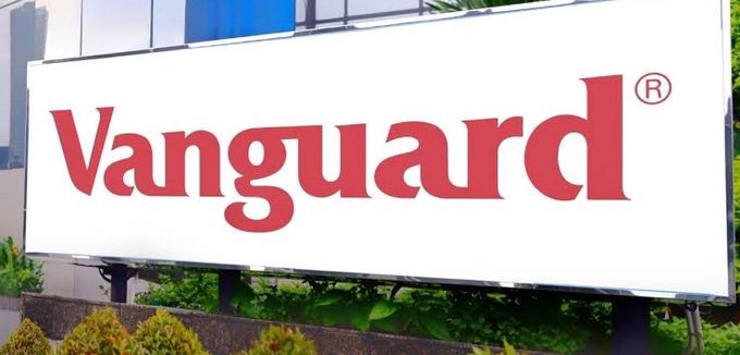 A Vanguard-branded sign stands outside a building, visually anchoring the company's name to the post's discussion of Vanguard's evolving digital asset strategy and new leadership focus on tokenization, stablecoins, and blockchain infrastructure.
