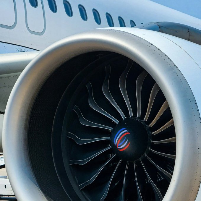 A close-up photograph shows a commercial aircraft jet engine with visible fan blades and the manufacturer's logo on the central hub, set against the white fuselage with passenger windows in the background.