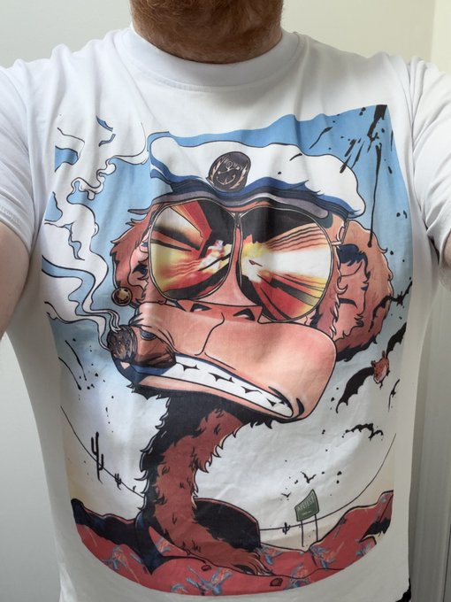 A white t-shirt featuring a cartoon graphic of a pink/red creature wearing a sailor hat and reflective sunglasses.