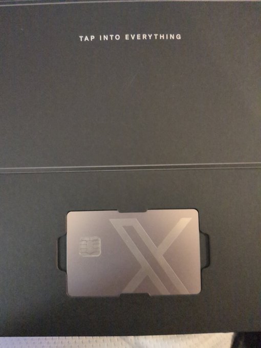 A metallic card with a large 'X' engraved on it, featuring a chip, presented in black packaging with the text 'TAP INTO EVERYTHING'.