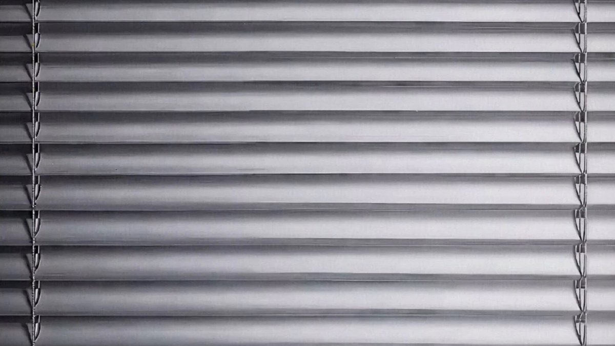 The image shows a close-up view of a pair of blinds, which are made up of vertical slats that cover an entire window. The blinds have a silver color with horizontal lines running across them, giving them a unique appearance. The background is a light brown color, providing a neutral backdrop for the blinds. The image also contains text that reads "Focus on what is in the image and how it relates to the post". This suggests that the focus of the image should be on the blinds themselves rather than on the context or content of the post.
