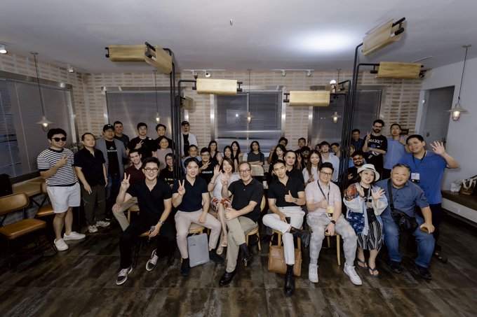 A group of over 70 builders, founders, and investors pose for a group photo at the Builders Happy Hour in Ho Chi Minh City, an official Conviction side event co-hosted by @apacdao, @ETHGlobal, and @utila_io. The attendees, dressed in casual attire, gather in a warmly lit venue, smiling and making peace signs as they celebrate Asia's vibrant Web3 community.