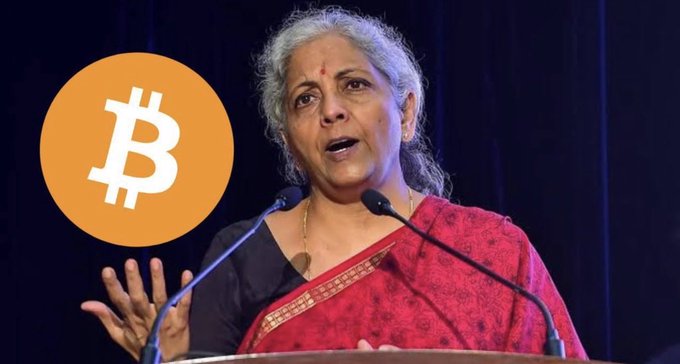India’s Finance Minister Nirmala Sitharaman speaks at a podium beside a prominent Bitcoin symbol. The image supports the post’s warning about FIU-IND issuing PMLA non-compliance notices to 15 crypto platforms, including WEEX, Bitunix, and BloFin.