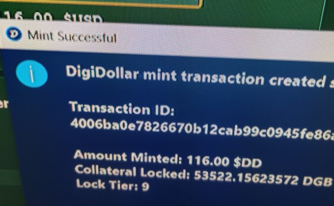 A close-up photograph of a computer screen showing a successful DigiDollar mint transaction, displaying a Transaction ID, an Amount Minted of 116.00 $DD, Collateral Locked of 53522.15623572 DGB, and Lock Tier 9.