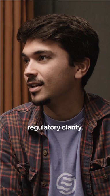 A man with dark hair and a goatee, wearing a plaid shirt over a purple t-shirt, is shown in profile view against a warm background. The image features the text "regulatory clarity." overlaid on his shirt, aligning with the post's discussion about how institutional adoption of crypto accelerates once frameworks become clear.