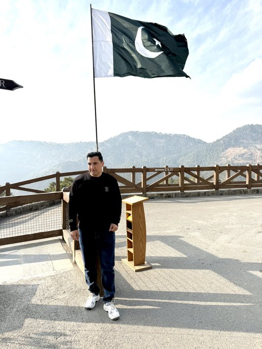 A man stands proudly at what appears to be the Pakistan-China border crossing, with the Pakistani flag waving behind him against a mountainous backdrop. The image embodies the post's message about taking that first step—his journey to this milestone destination serves as a powerful reminder that meaningful achievements come from simply starting where you are and keeping moving forward.