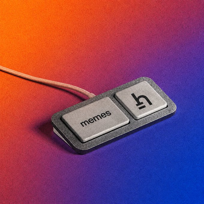 A 3D-rendered close-up of a metallic keyboard switch keycap labeled 'memes' connected to a cable, displayed against a vibrant orange-to-purple gradient background.
