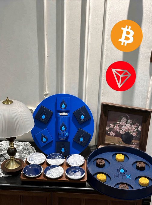A Mid-Autumn Festival gift box from Huobi HTX is displayed, featuring the brand's signature blue color and flame logo, accompanied by an open tray of mooncakes and decorative bowls, aligning with the post's celebration of the holiday and the company's thoughtful gift package.