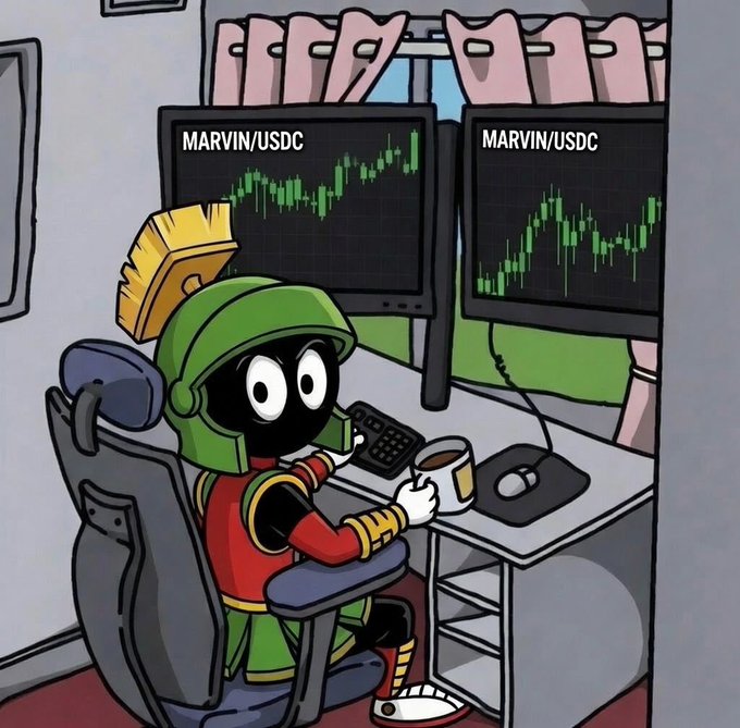 Cartoon illustration of Marvin the Martian sitting at a desk in a red robe, holding a coffee cup while viewing dual monitors displaying 'MARVIN/USDC' candlestick charts in green.