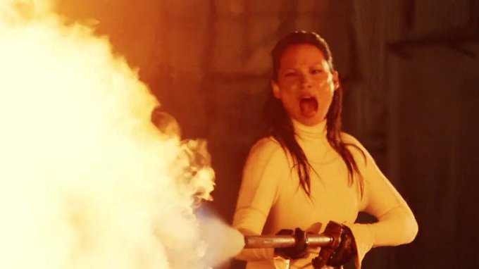 A fierce young girl screams while unleashing a massive stream of fire from a flamethrower, embodying the intense, relentless, and unstoppable energy that the post says will be brought to Solana every day of the year.