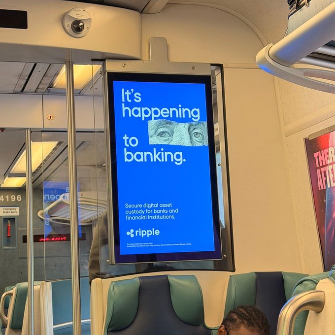 A digital advertisement inside a subway/train car displays a Ripple ad reading "It's happening to banking. Secure digital asset custody for banks and financial institutions," directly tying to the XRP post by promoting Ripple's institutional crypto custody services.