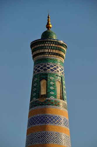 A tall Islamic minaret with intricate turquoise, gold, and white tilework rises against a clear sky, visually representing the "Minaret Islamic Tower" token featured in the post.
