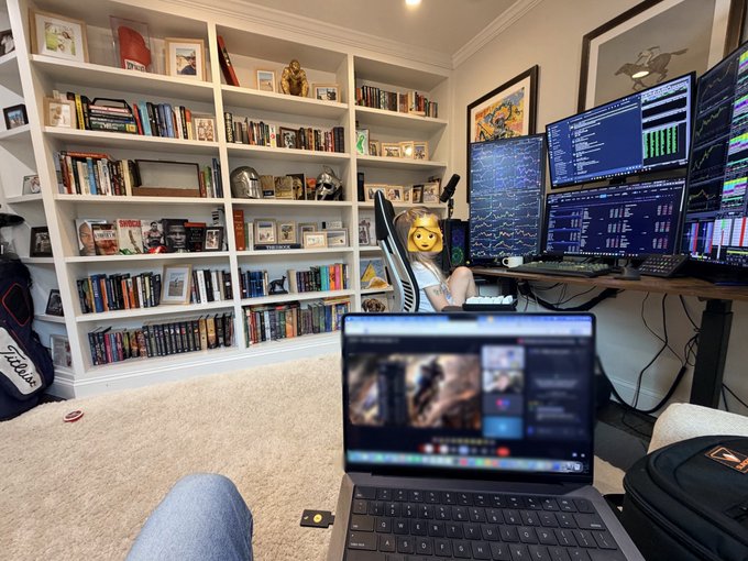 A child sits in a gaming chair at a multi-monitor trading setup displaying cryptocurrency data from KrakenFX, with the mini numeric keypad on the laptop cleverly positioned like a spaceship control panel. The home office, filled with bookshelves and collectibles, has been transformed into an imaginative cockpit where the child pretended to pilot through the trading charts.