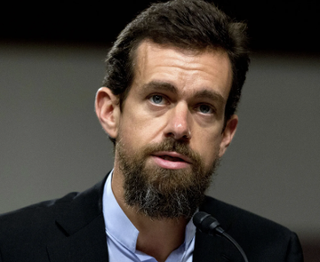 A bearded man in a dark blazer and light blue shirt speaks into a microphone during what appears to be a formal hearing or panel discussion, likely representing a Wall Street banking analyst commenting on Block's initiation by Barclays.