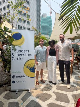 Three people posing at an outdoor event next to a 'Founders & Investors Circle' banner, brought to you by Frachtis and Flow Capital.